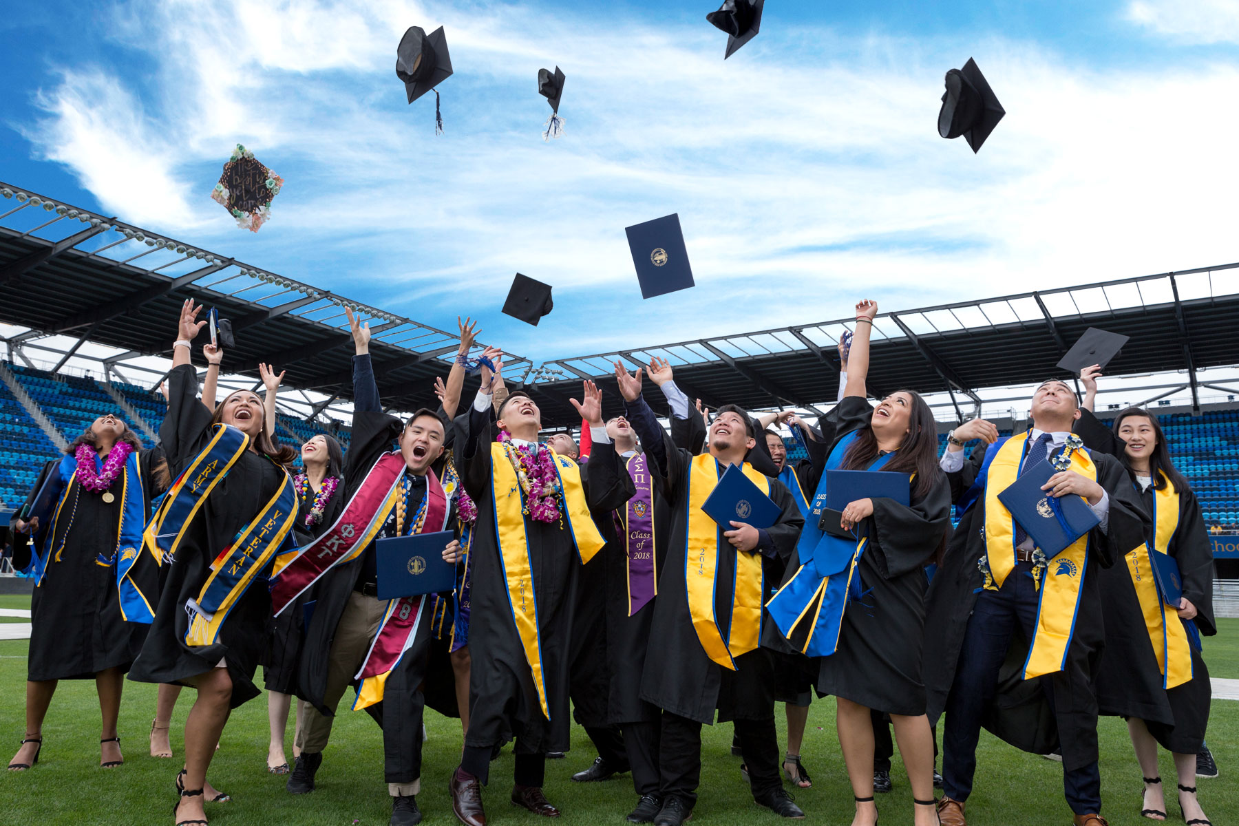 Just graduated students in graduation robes throwing their hats into the air