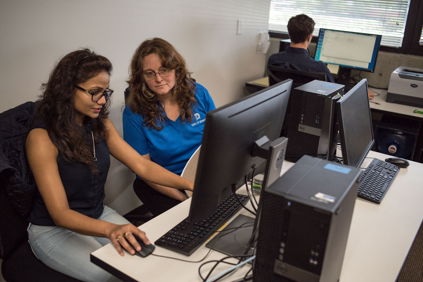 Two faculty members working on a computer together