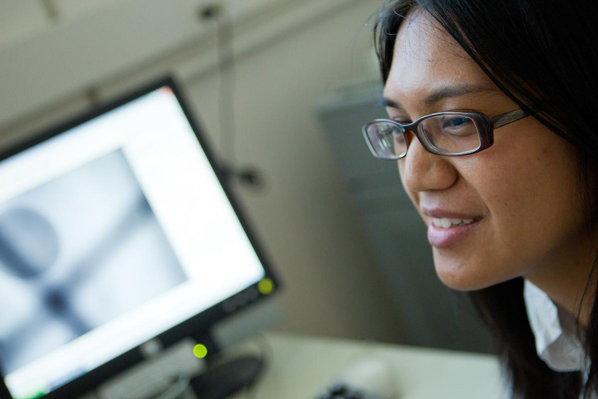 SJSU student smiles in front of a computer screen