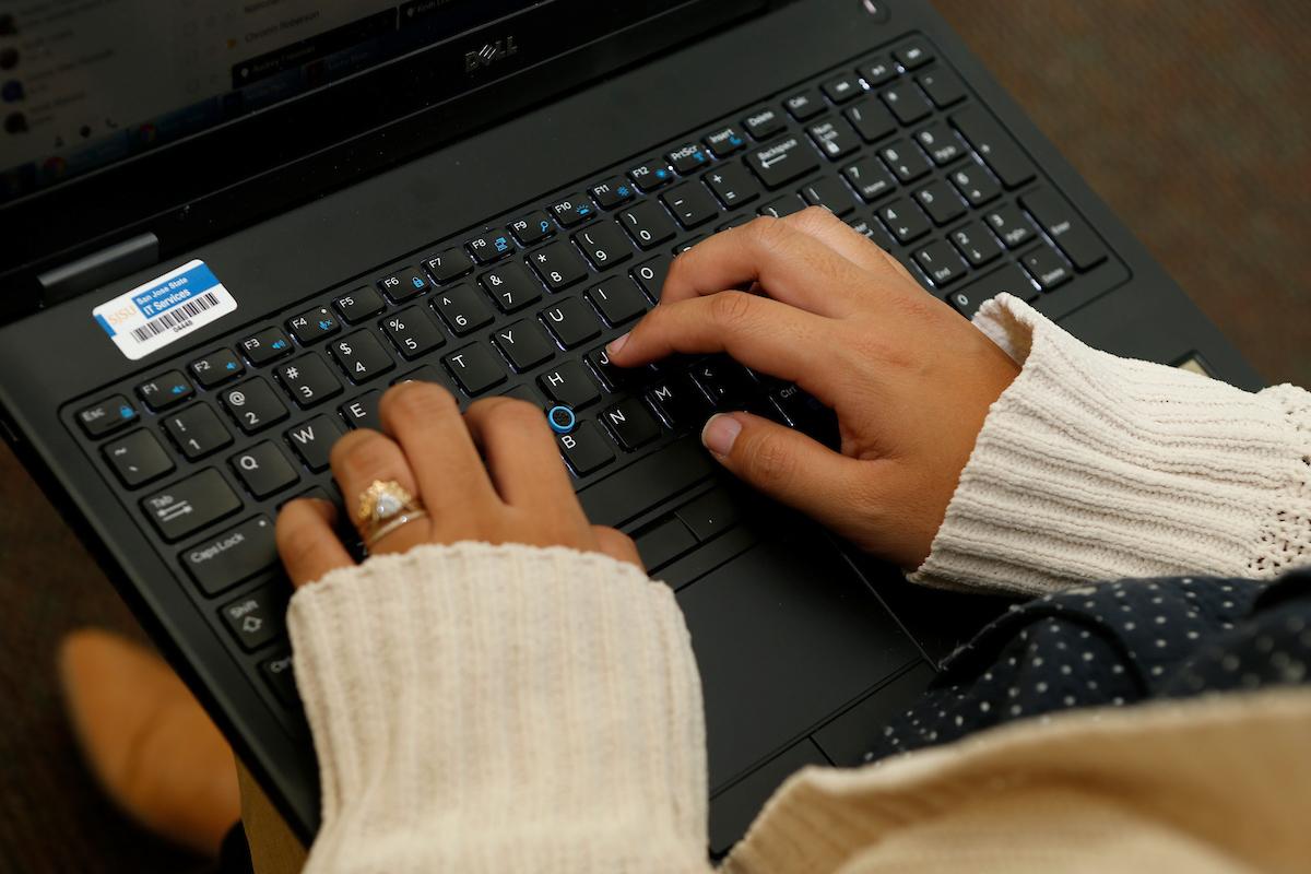 SJSU faculty types on computer during a presentation
