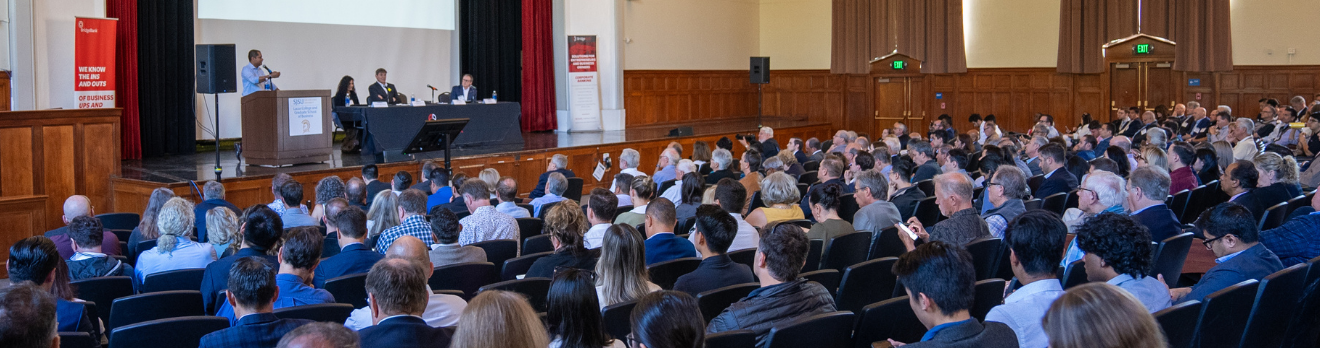 Business professional presenting to a crowd of over 300 people at the SJSU Economic Summit