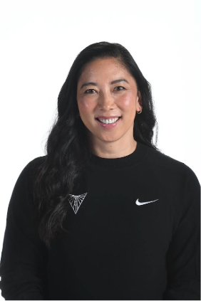 Woman with long dark hair smiling at the camera against a light background, wearing a black sweater.