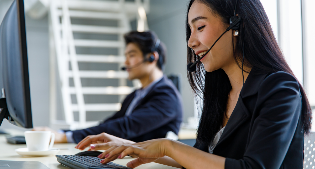 Employees on the computer with phone headsets.
