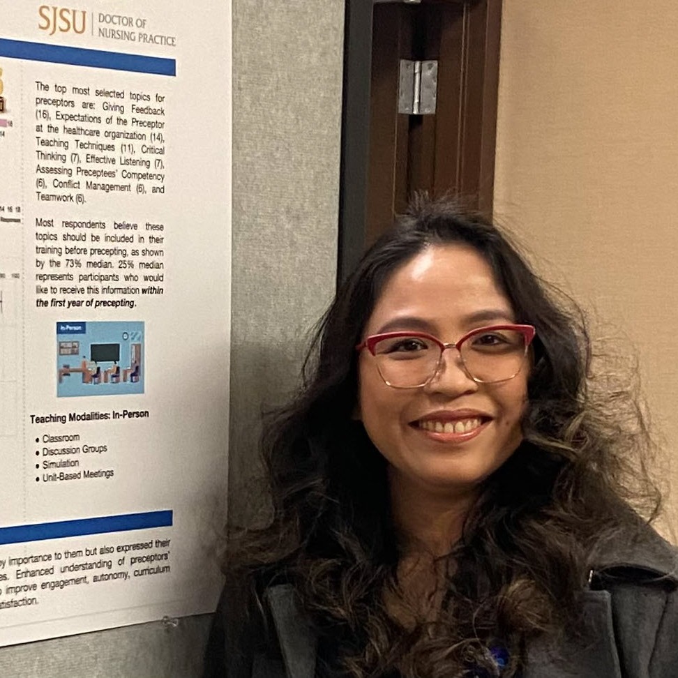 Janice Valadez standing in front of the poster she made, which represents her DNP project.