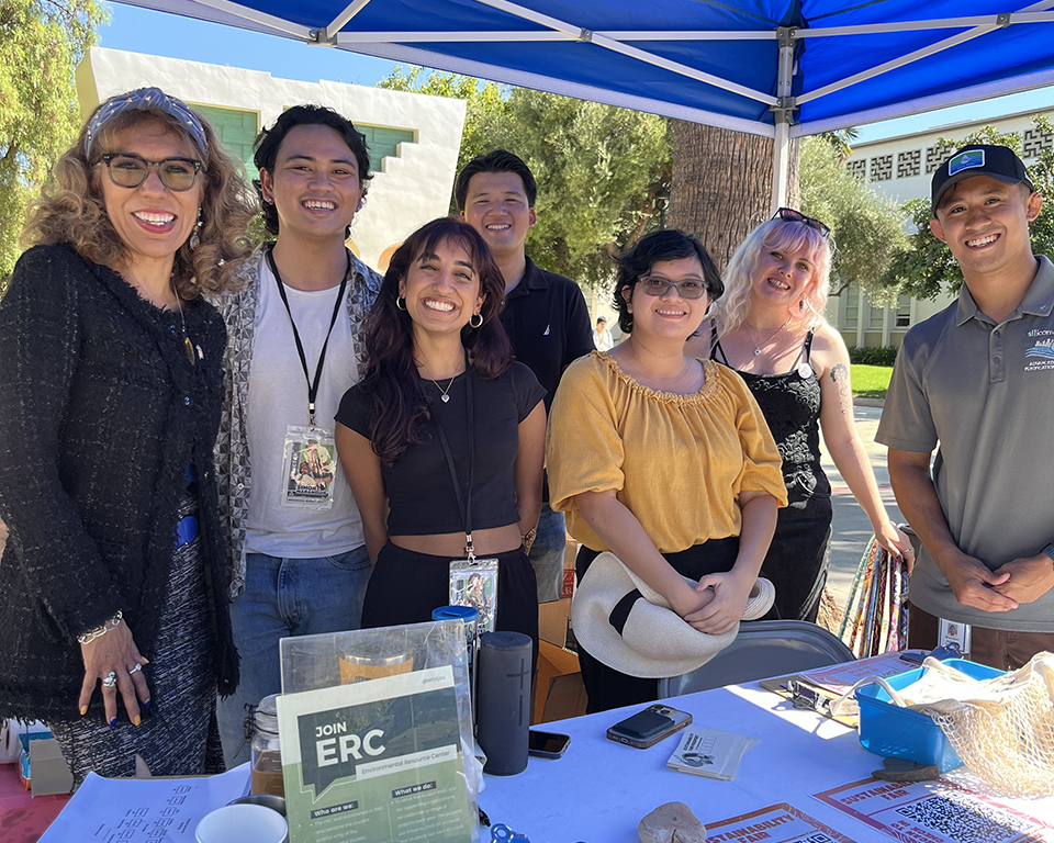 SJSU President, Cynthia Teniente-Matson, with students posing under a shade structure during a tabling event at the annual Fall Sustainability Fair, Abundance. Without Waste