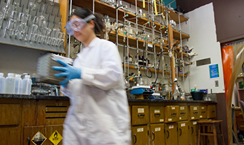 battery scientist in lab gear carries things in lab