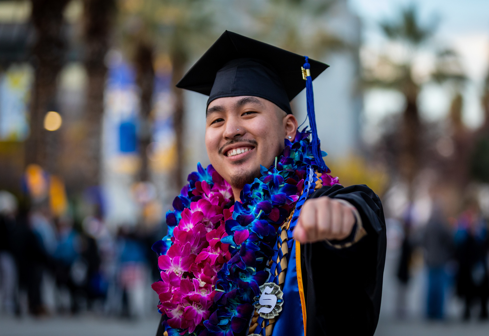 Upclose of graduating student in regalia pointing at the camera