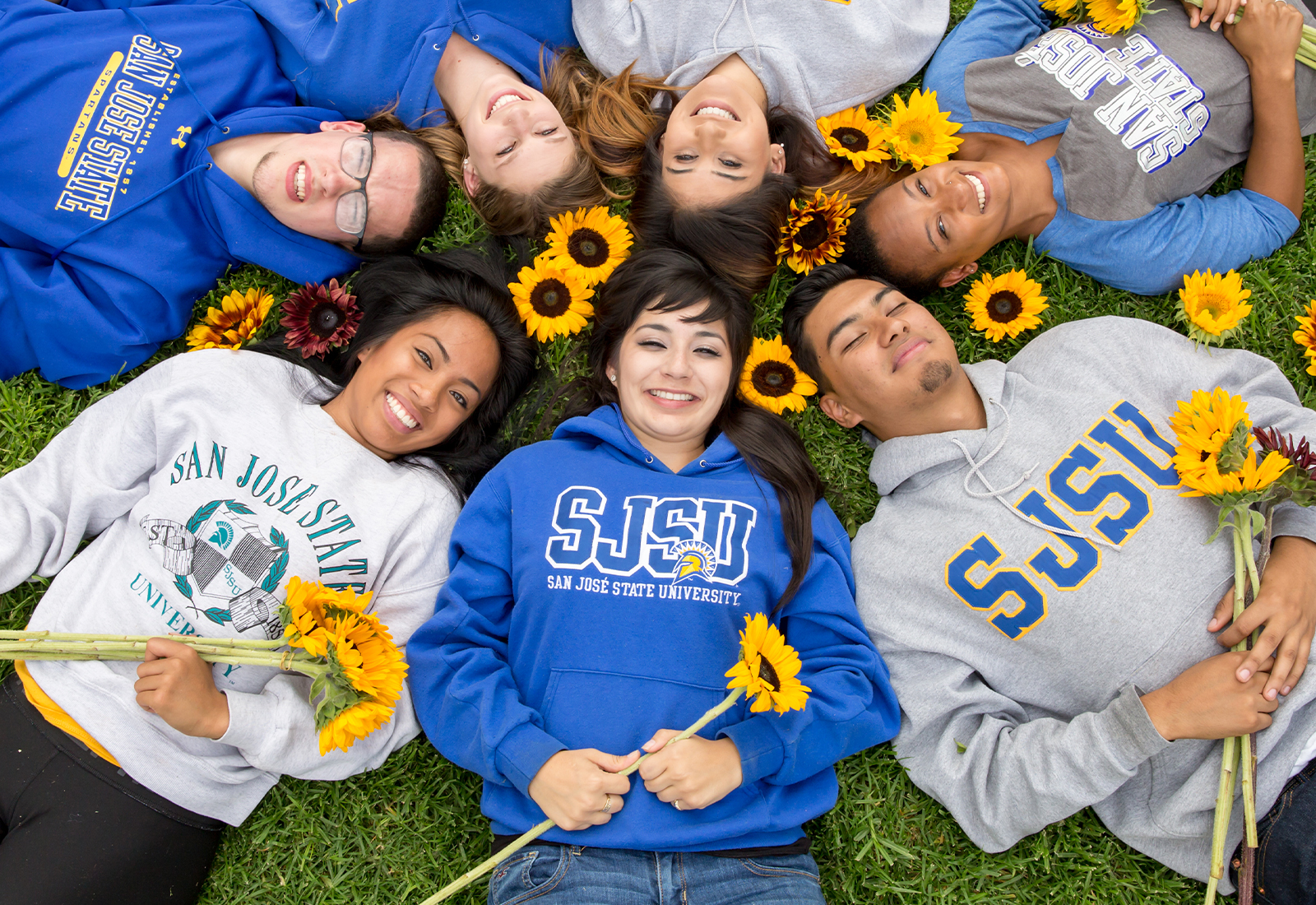 Students in a circle on the lawn holding sunflowers