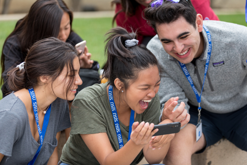 People looking at a mobile phone and laughing.