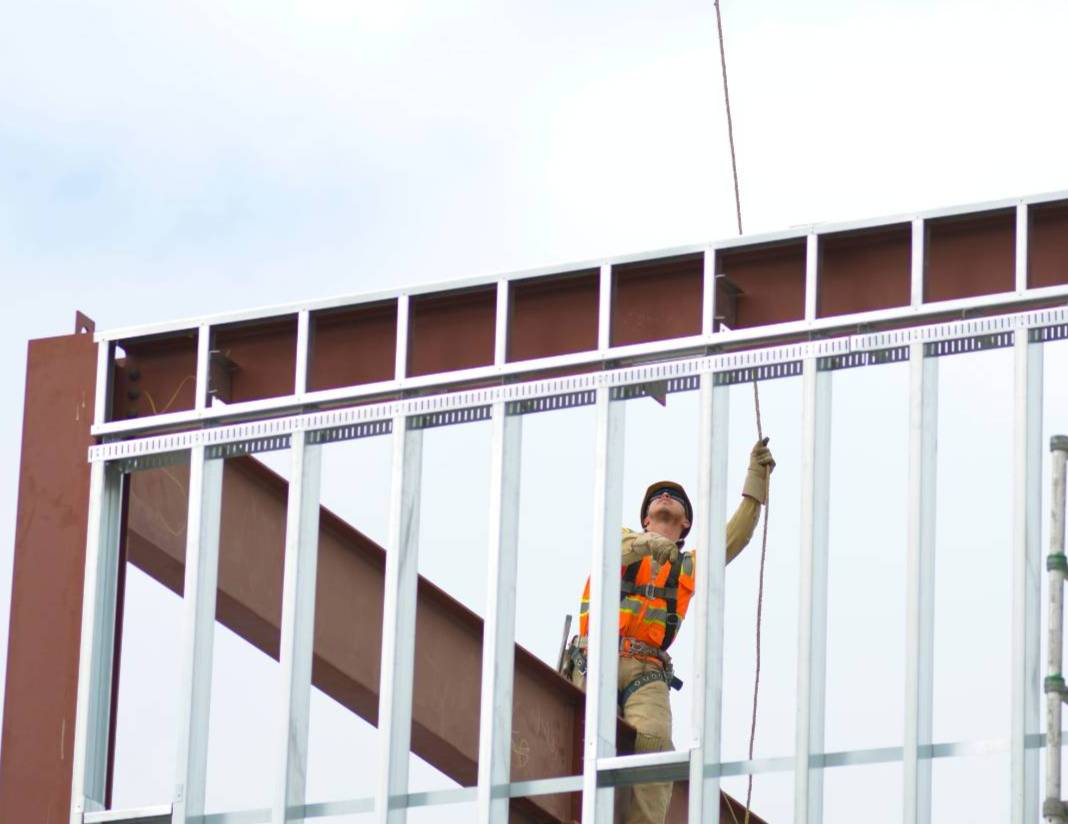 final touches being added to the student union building. crane carrying cinder beam to place on top of building.